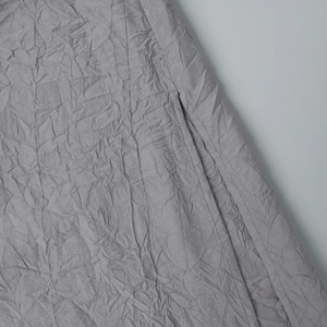 Détail du tissu à texture froissée gris clair avec poche latérale et couture sur la robe