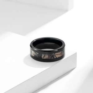 Macro detail of men's black tungsten ring with realistic camouflage wood grain inlay