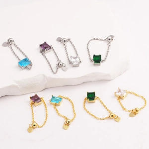 Detail of 18K gold plated chain rings featuring rectangular emerald cubic zirconia and heart charms