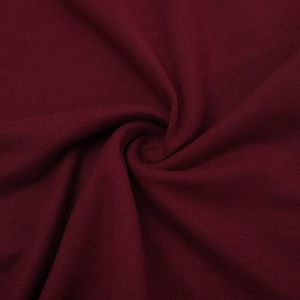 Détail macro du tissu tricoté bordeaux montrant le drapé doux et la qualité du textile