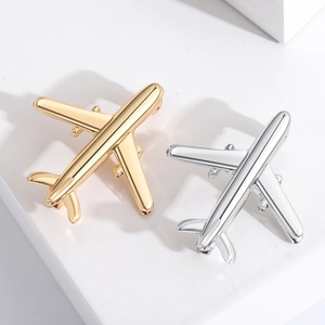 Close-up of sleek gold and silver airplane-shaped lapel pins on a clean white background
