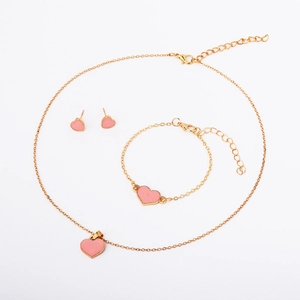Detail view of pink enamel heart necklace, bracelet, and earrings in gold-tone setting