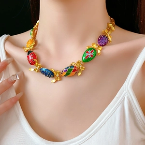 Dettaglio collana vintage dorata con ciondoli in smalto colorato e fiocchi con cristalli