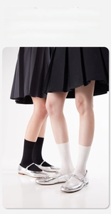 Nahaufnahme von gerippten Socken in Schwarz und Weiß mit silbernen Mary Jane Schuhen