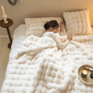 Detailed view of cream faux fur blanket with square embossed texture and soft plush material