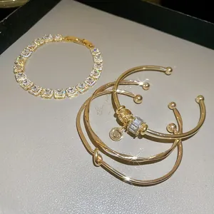 Détails d'un ensemble de bracelets dorés de luxe avec zircons et design noué