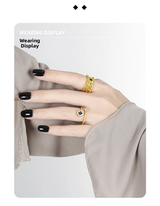 Wearing display of two gold open rings featuring blue zircons and vintage woven mesh design