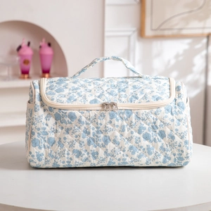 Quilted floral makeup bag with top handle and double zipper on a white table
