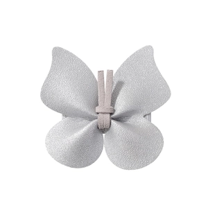 Macro detail of a silver butterfly hair clip made of textured leather and soft suede fabric