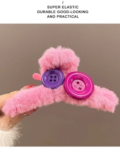 Detailed view of the pink plush hair claw clip featuring large colorful decorative buttons