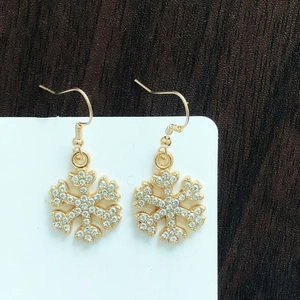 Detailed close-up of gold snowflake earrings with sparkling white rhinestones on display