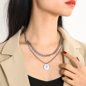 Macro detail of silver double-layer necklace featuring chunky Cuban links and coin pendant