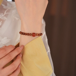 Close-up of beaded bracelet with red agate stone and gold spacers on a model wrist