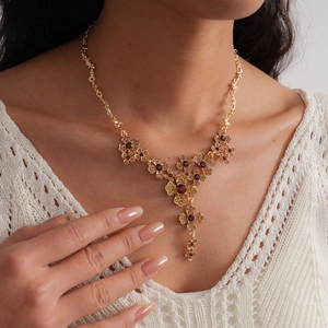 Detail of flower tassel necklace with red stones on model in vintage golden style