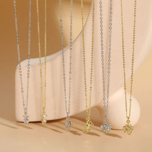 Selection of bear and elephant zircon pendants in gold and silver on pink display