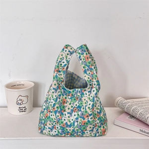Detail view of floral corduroy wrist bag with blue checkered lining and textured fabric
