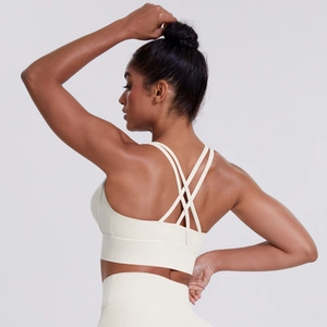 Detail of cross-back thin straps on a cream yoga bra with high-elastic matte fabric