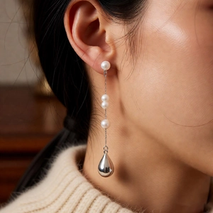 Close-up of French vintage drop earring with three white pearls and silver pendant
