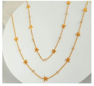 Detail of a gold-tone star pendant necklace with white crystals on a white pedestal