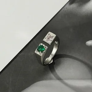 Minimalistischer silberner Ring mit grünem Edelstein und Sternmuster auf Hintergrund
