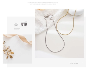 Minimalist gold and silver box chains on white textured background in detail view