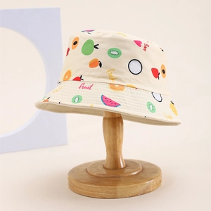 Close-up of beige cotton bucket hat with colorful fruit prints and wood stand display