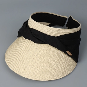 Close-up of woven straw visor showing black ribbon bow and gold metal logo detail