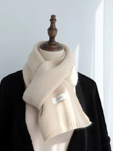 Detail of beige knitted scarf with woven texture and small FEIDING brand label