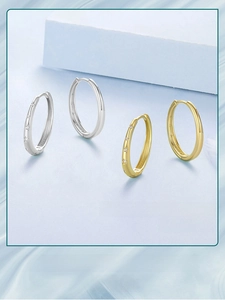 Detailed view of silver and gold star-engraved hoop earrings on a light blue background