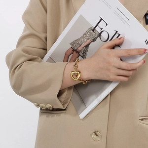 Goldenes Titanstahl-Armband mit Herz-OT-Verschluss, getragen von einem Model im Fashion Look