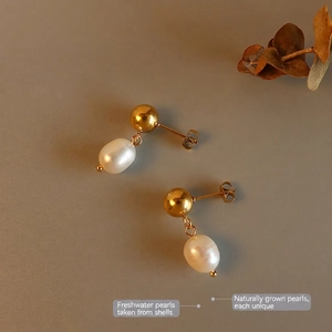 Elegant gold stud earrings with natural freshwater pearls on a minimalist dark background