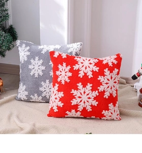 Gros plan des housses de coussin de Noël en peluche avec flocons de neige brodés rouge et gris