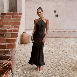 Close-up of elegant black satin halter neck dress with backless design in a garden