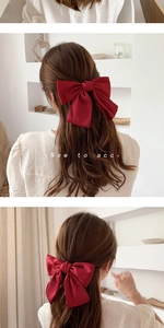 Detail of a large red fabric double-layered bow hair clip shown on model's hair