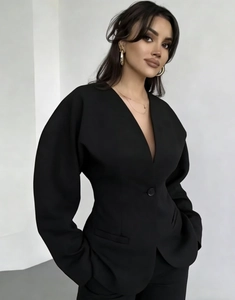 Détail de la veste de tailleur noire cintrée avec col en V et bouton structuré