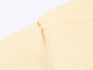 Gros plan détaillé montrant les coutures et le tissu coupe-vent jaune clair du manteau