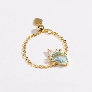 Detail of adjustable gold chain ring with blue pear-cut gemstone and micro-pave diamonds