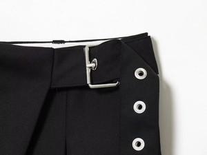 Detail of black blend trousers featuring silver metal buckles and eyelets on the waist