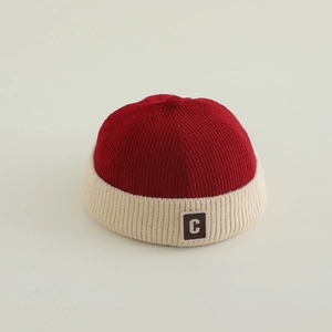 Close-up of kids red and cream knit miki hat featuring a brown letter C patch detail