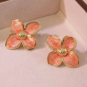 Detail of vintage flower stud earrings with orange enamel texture and gold finish