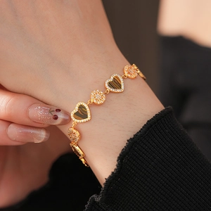 Detailed view of a gold-plated heart bracelet with tiger eye stone and pavé zircon on wrist