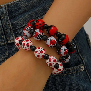 Détail de perles à motifs de coccinelles et cœurs sur trois bracelets de perles empilables