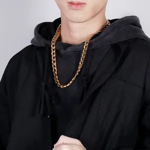 Close-up of a thick gold-tone curb chain necklace worn by a model on a grey background