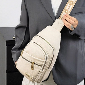 Detail of beige lychee textured PU leather crossbody bag with embroidered strap and gold zippers