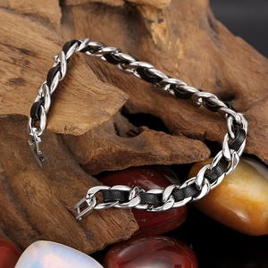 Gros plan du bracelet tressé en cuir noir et acier inoxydable sur bois naturel