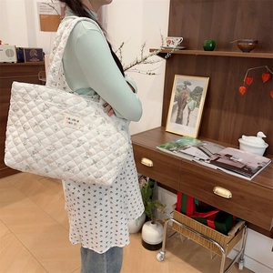 Detail of quilted tote bag with floral bunny patterns on a soft knit fabric texture