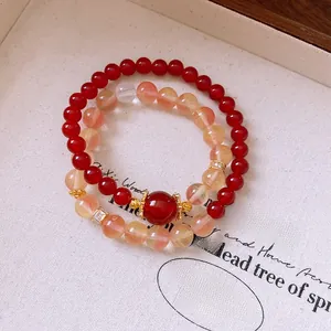 Détail de bracelets en perles rouges et ambre avec des éléments dorés et ciselés