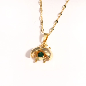 Macro detail of gold ladybug pendant with green gemstone and sparkling diamonds