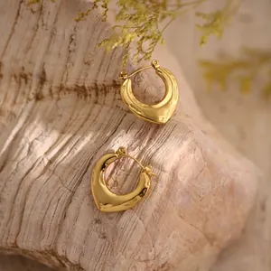 Detailed view of chunky heart-shaped gold hoop earrings with irregular hammered texture