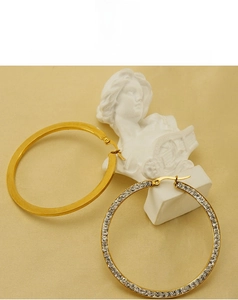 Detail of 18k gold plated hoop earrings with one polished and one diamond-set ring
